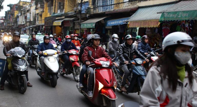 Rua movimentada do Bairro Antigo de Hanói com motos e fachadas coloridas — o coração histórico da capital do Vietnã