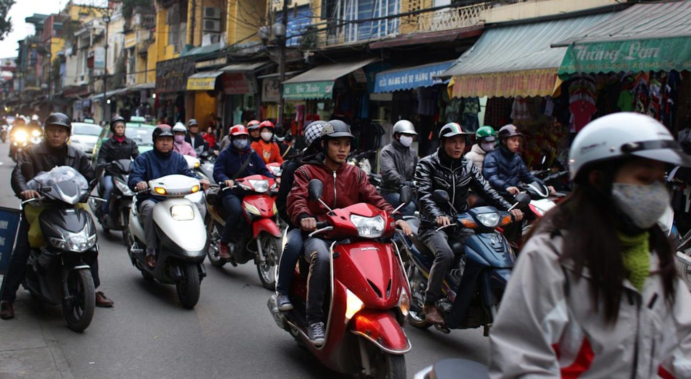 Rua movimentada do Bairro Antigo de Hanói com motos e fachadas coloridas — o coração histórico da capital do Vietnã